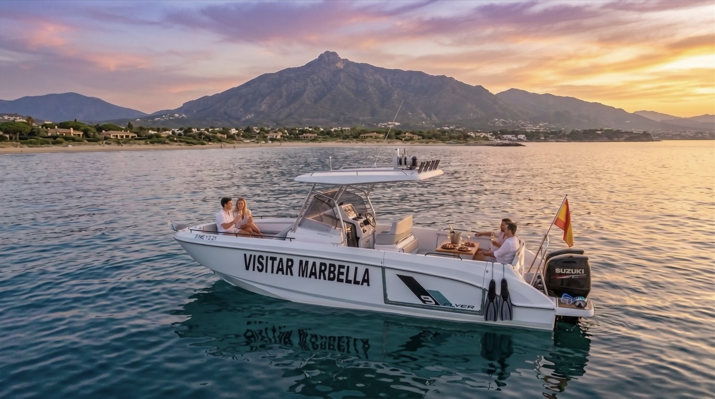 The Visitar Marbella boat at anchor at sunset with guests aboard, La Concha mountain silhouetted behind