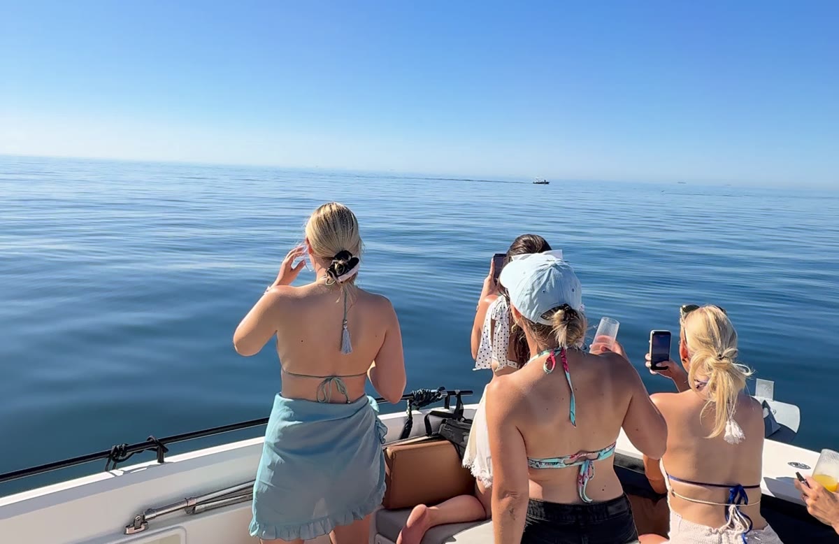 A group of guests sitting on the bow of the boat scanning flat calm water off Marbella, La Concha mountain behind them